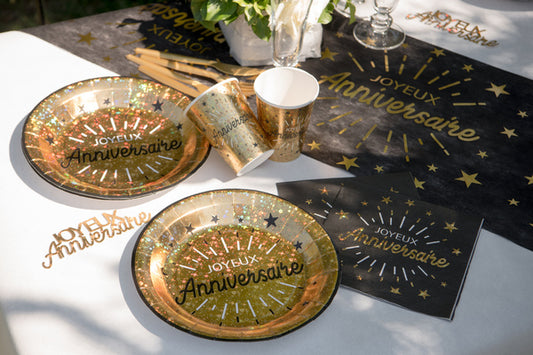 Mise en situation sur table des assiettes en carton Joyeux anniversaire pour fête noir et or chic métallisées
