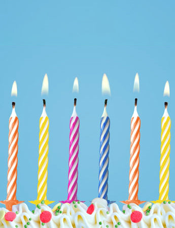 Gros plan sur les flammes des bougies magiques d'anniversaire multicolores à rayures avec supports