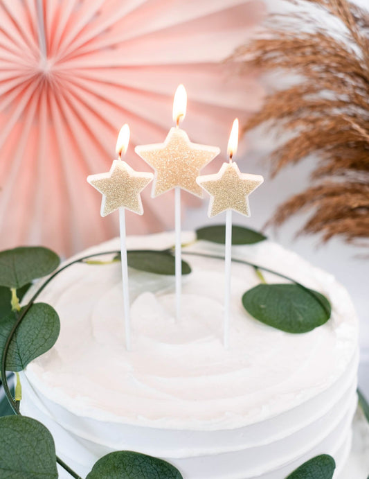 Gros plan sur les bougies allumées sur un gâteau des 3 bougies sur pic étoiles pour fête