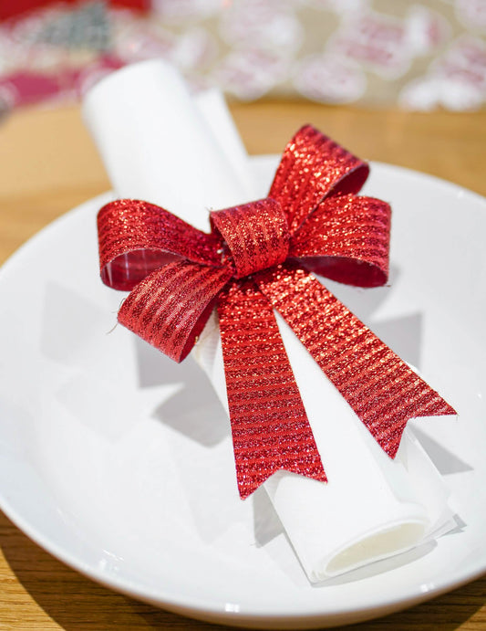 Mise en situation sur une serviette des nœuds pour décoration rouges et brillants