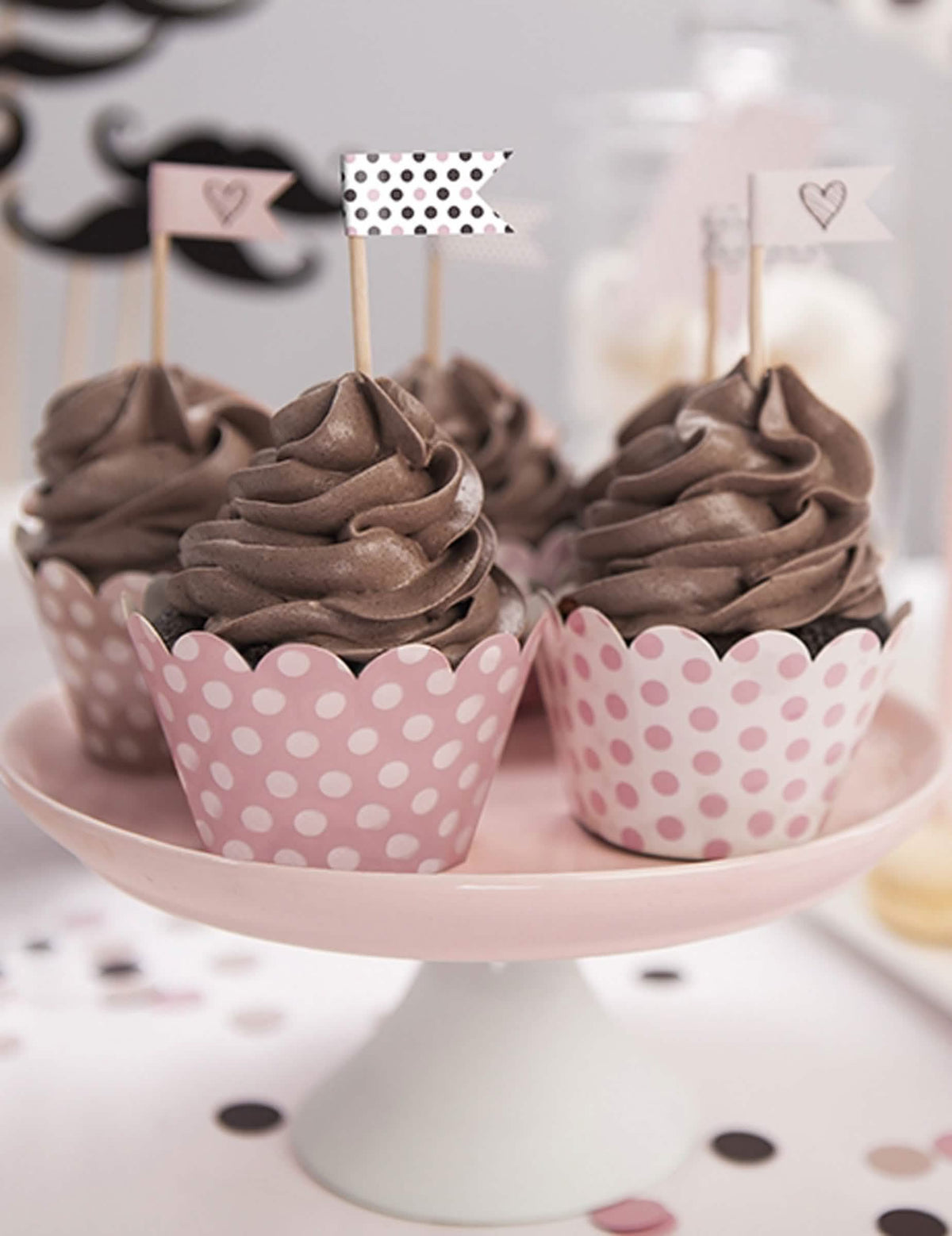 Kartonból készült púderrózsaszín pöttyös cupcake-borítások bemutatása helyzetben