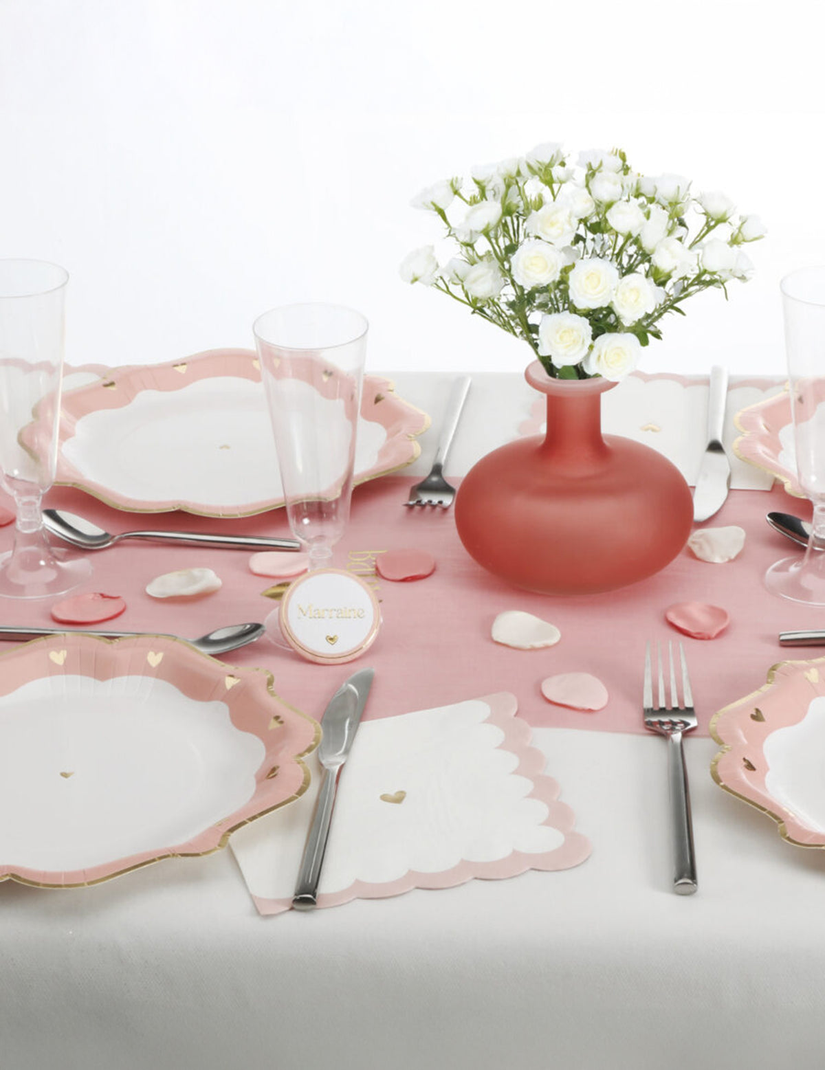 Mise en situation sur une table de fête des pétales en satin pour décoration ivoire rose et vieux rose
