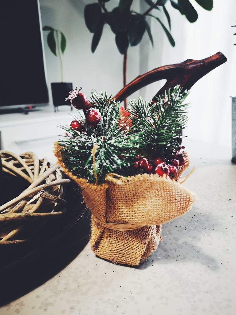 Détail du pot en toile de jute de la composition de Noël baies rouges et sapin enneigés