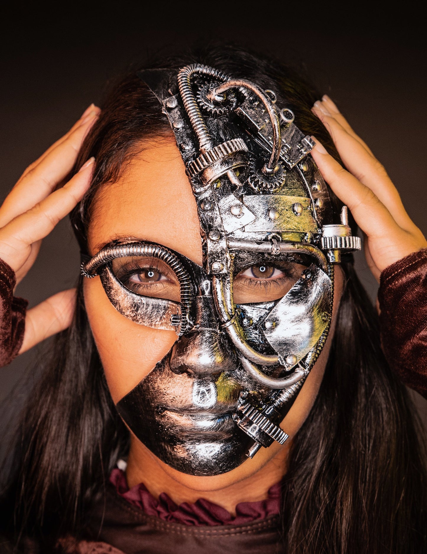 Vue de face avec les mains sur les tempes du demi masque robot Steampunk