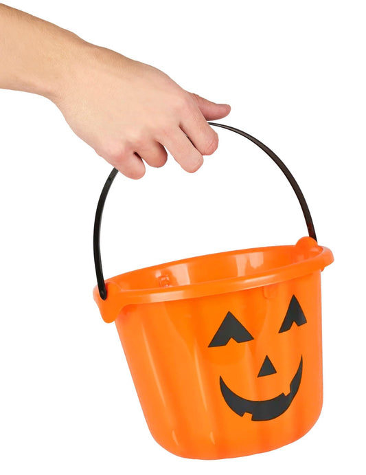 A halloween-i tök vödör egyik kézzel tartott fülének részlete