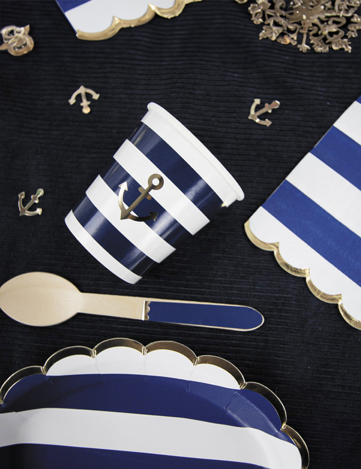 Mise en scène de table des serviettes festonnées en papier marinière bleu marine et blanc à bords dorés avec ancre