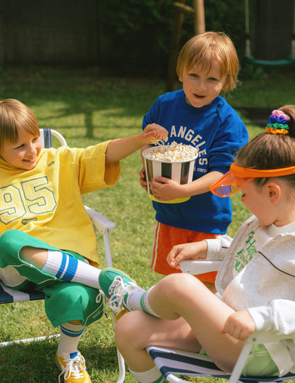 Enfants partageant du popcorn du pot à snacks en carton à rayures noires et blanches avec base jaune
