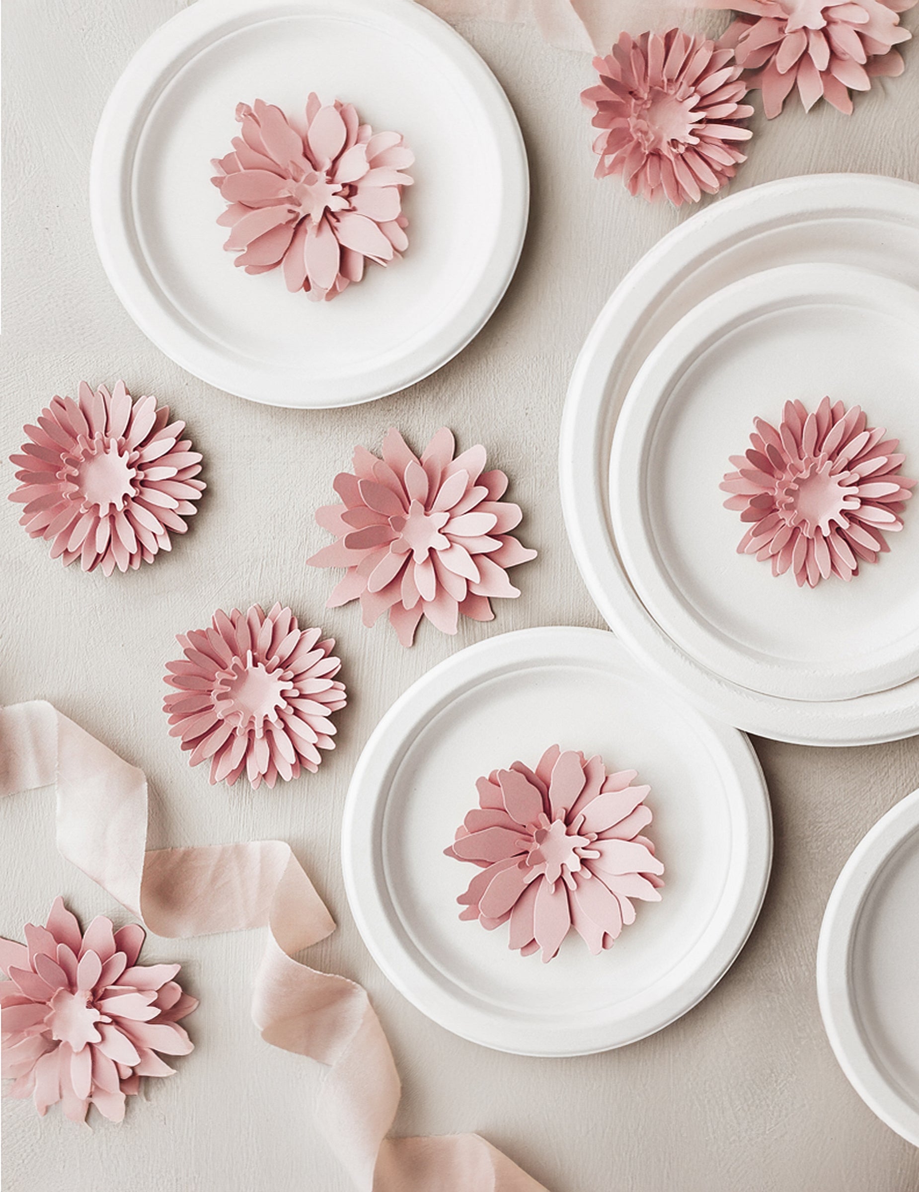Mise en scène sur des assiettes des fleurs en papier 3D pour décoration rose poudré