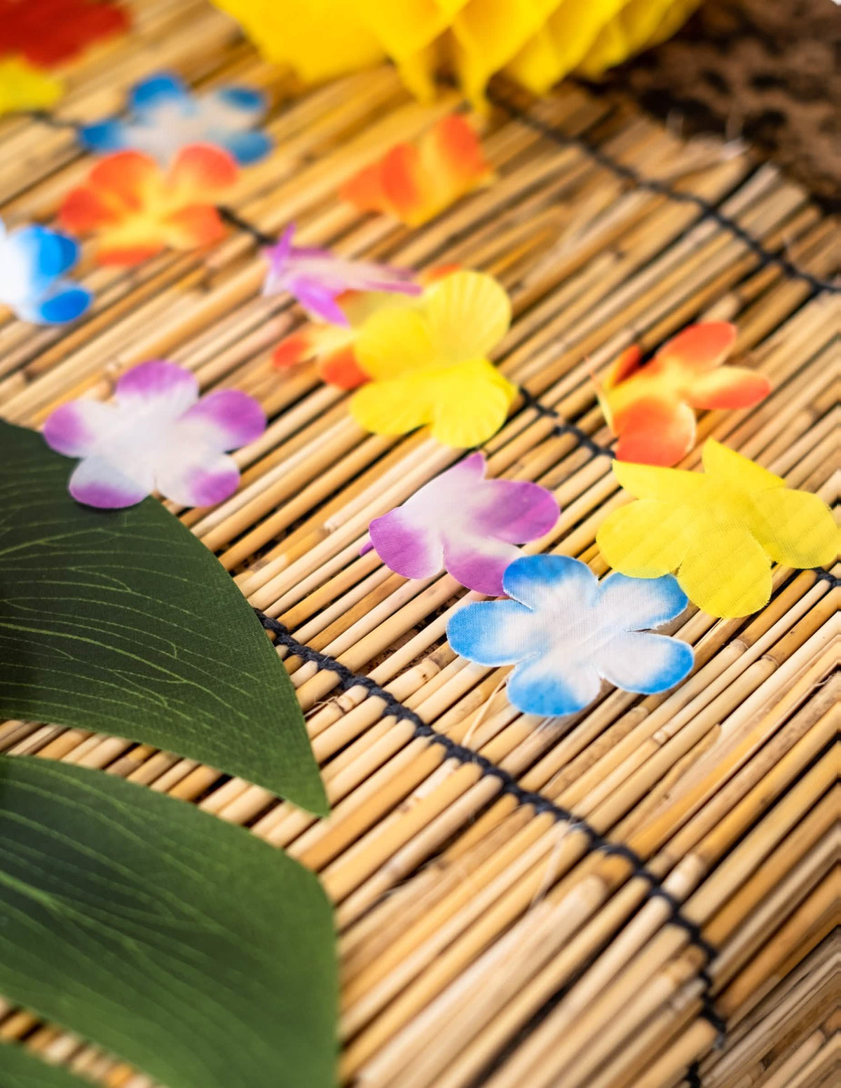 Bambuszszőnyegen elhelyezett hawaii dekoratív virágok
