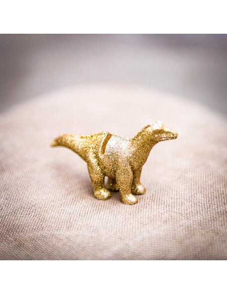 Gros plan sur les paillettes dorées du marque-place en résine dinosaure