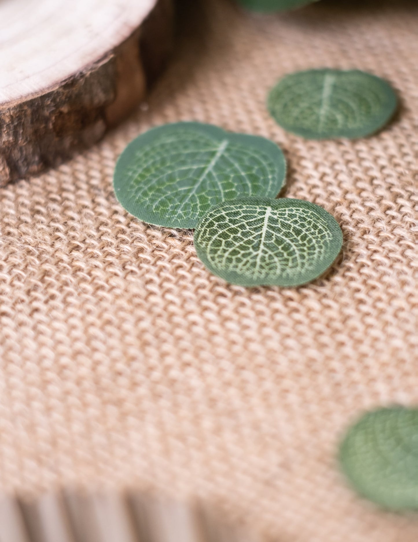 Détail sur fond en toile de jute des confettis feuilles d'eucalyptus mariage nature