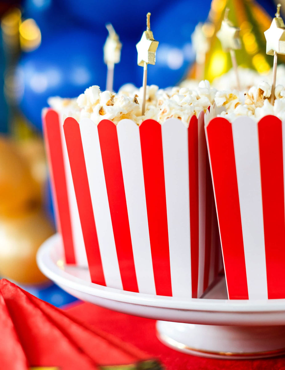 Közelkép a popcornról és a piros-fehér karton popcornos dobozok arany színű dísztüskéiről