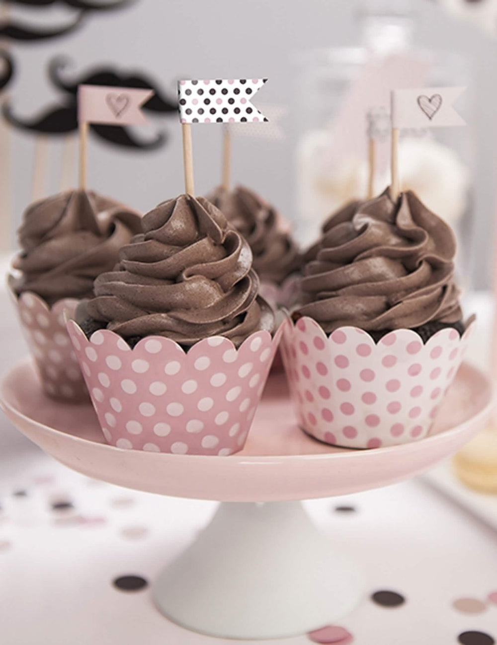 Kartonból készült púderrózsaszín pöttyös cupcake-borítások bemutatása helyzetben