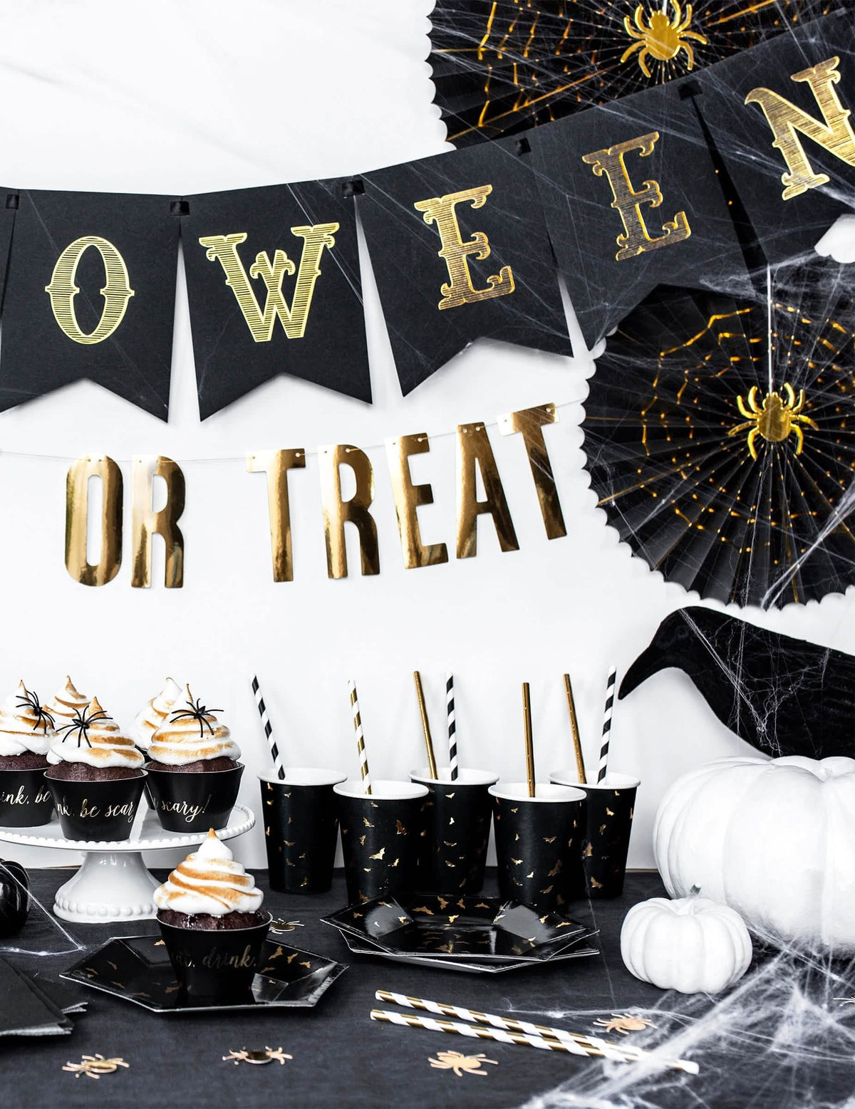 Halloweenre díszített asztalon elrendezve denevérmintás kartonpoharak