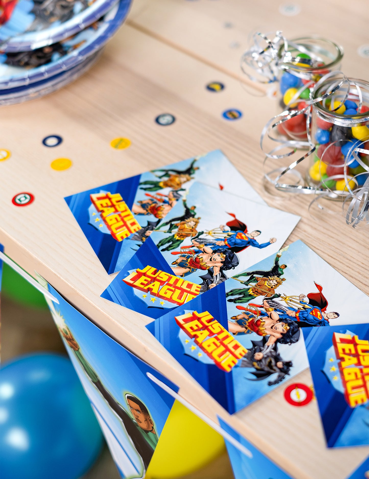 Mise en scène sur une table avec confettis des cartes d'invitation avec enveloppes Justice League