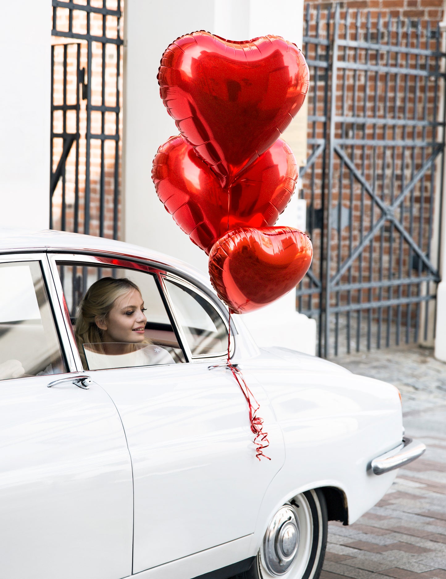 Mise en situation sur une voiture du ballon aluminium coeur pour fête rouge métallisé