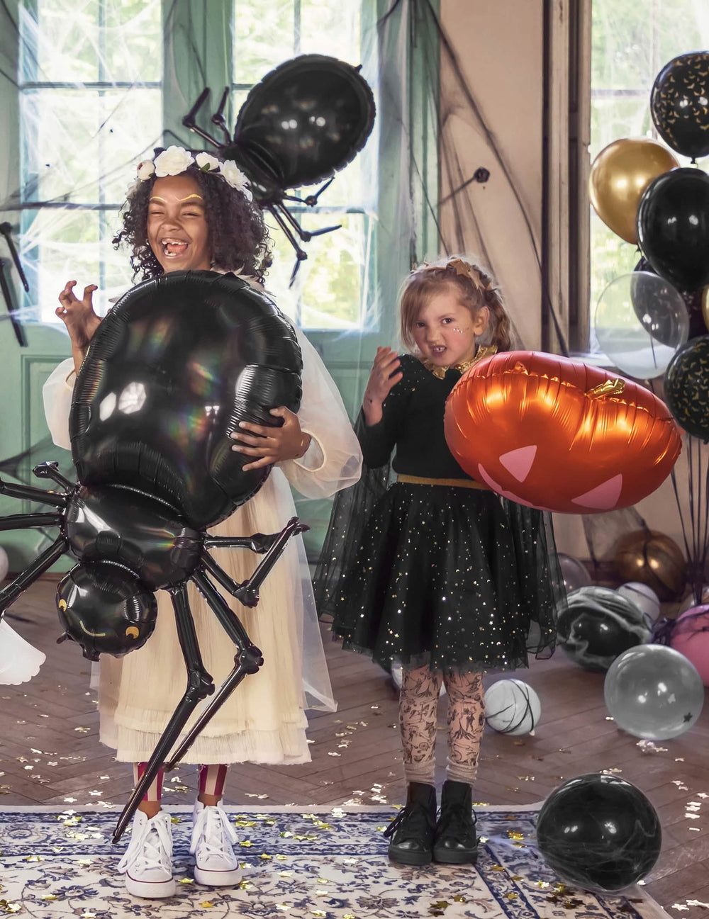 Gyermek, aki a halloween dekorációhoz való tök alakú alufóliás lufit tartja