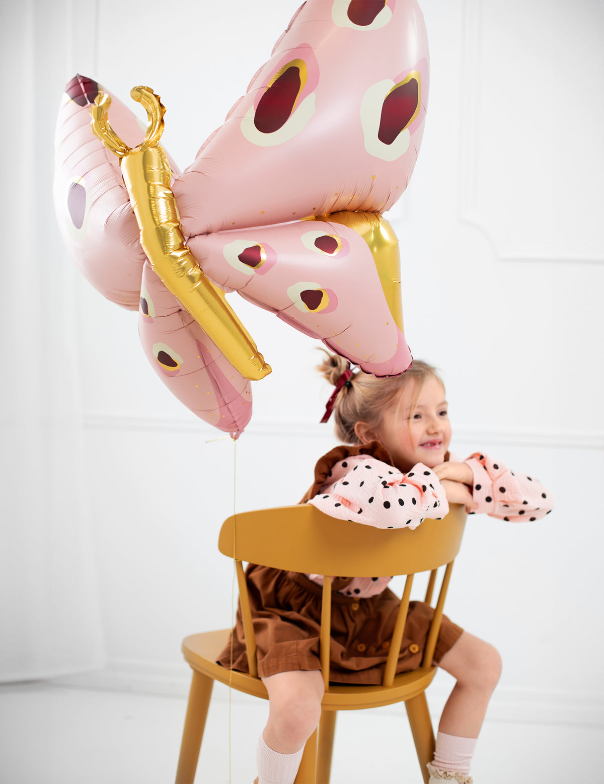 Mise en situation avec une enfant sur une chaise du ballon géant en aluminium papillon