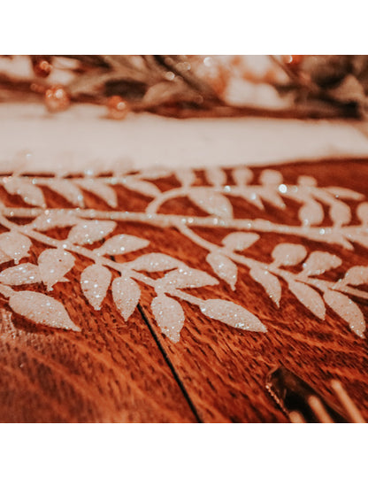 Gros plan sur les feuilles pailletées de la branche de feuillage à paillettes pour décoration blanche