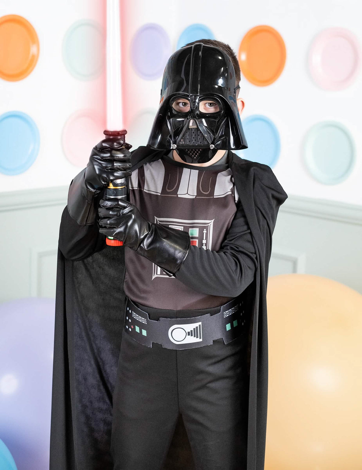 Közelkép a fiú klasszikus Darth Vader jelmezének mellkasáról és fénykardjáról