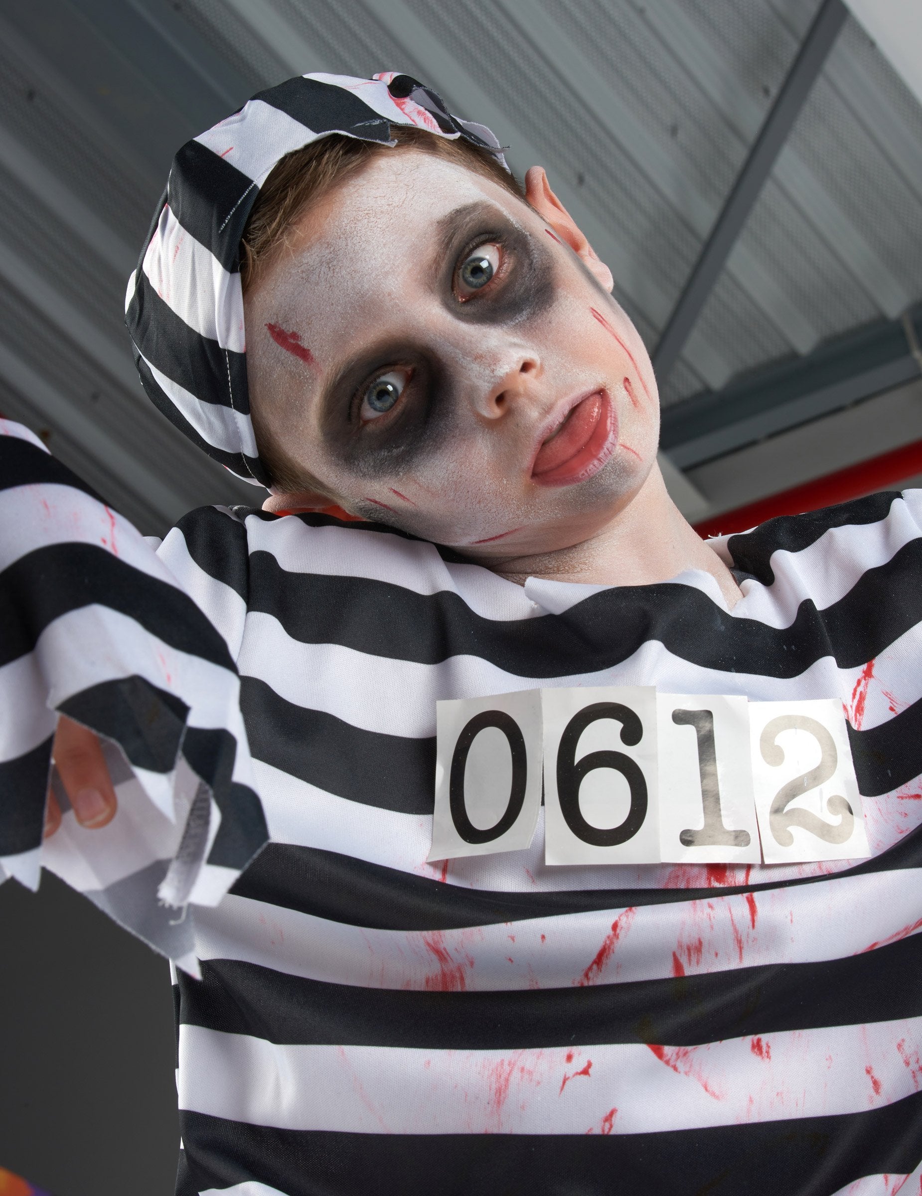 Közelkép a csíkos kalapról és az arcról a zombi börtönös jelmezben fiú Halloweenra