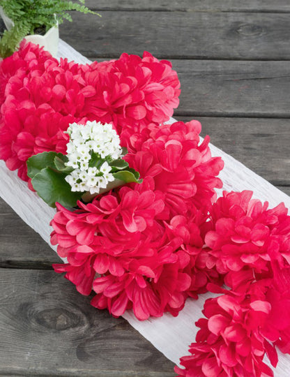 Mise en situation sur une table de la guirlande en papier fleurs rouges