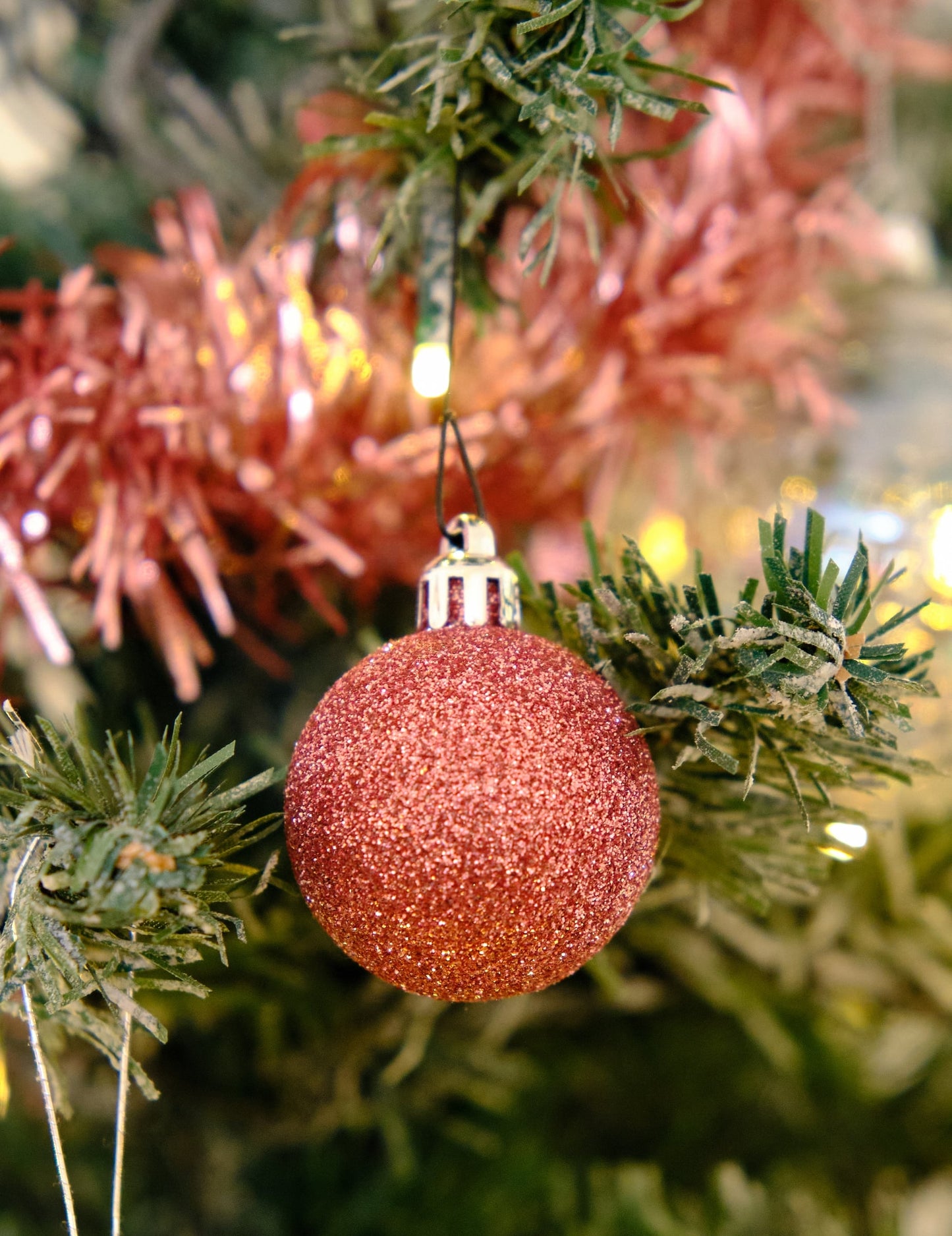 Gros plan sur une boule pailletée du kit de décorations de sapin rose gold