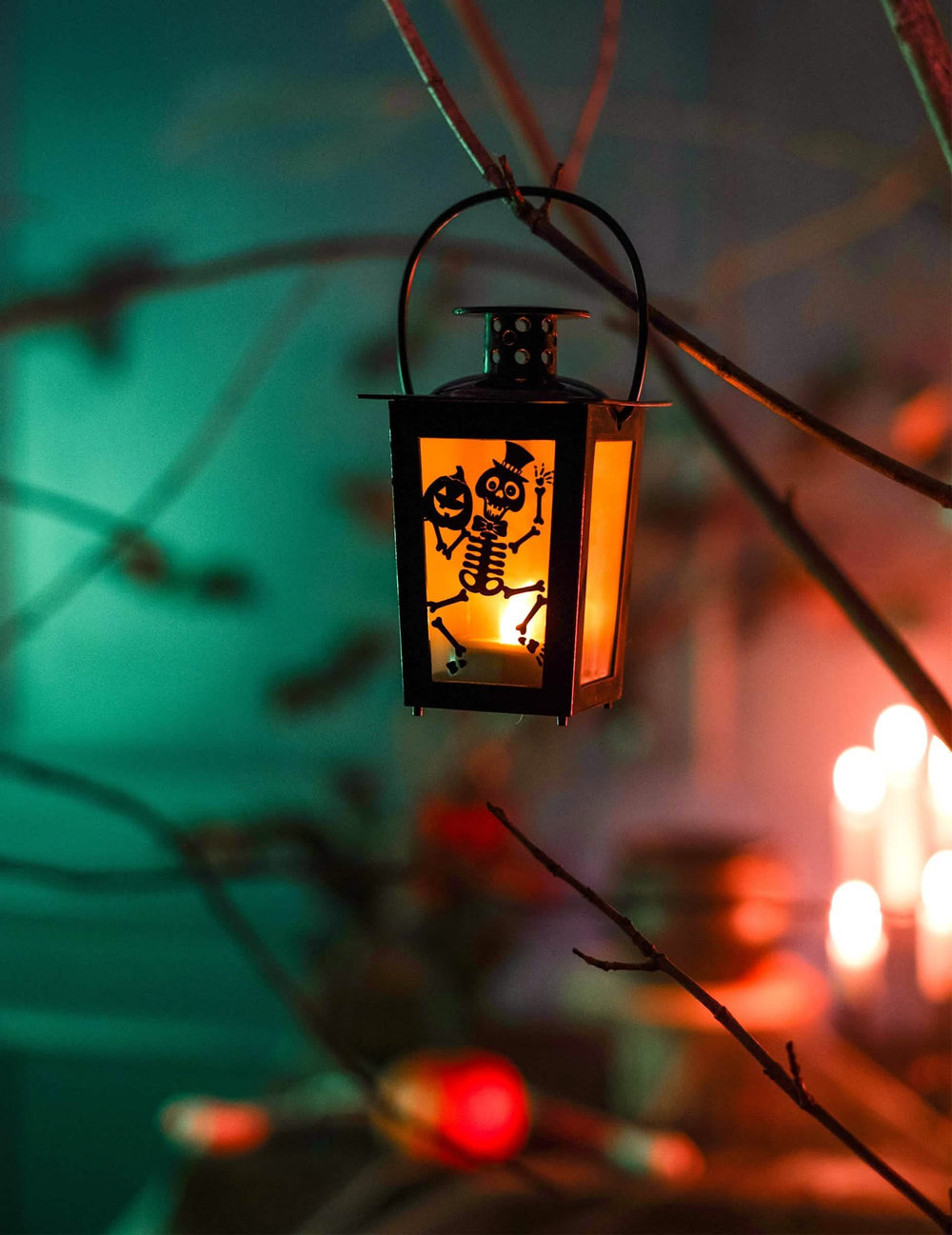 Függő díszlet egy ágon, halloween-i világító lámpás, csontvázzal és tökkel