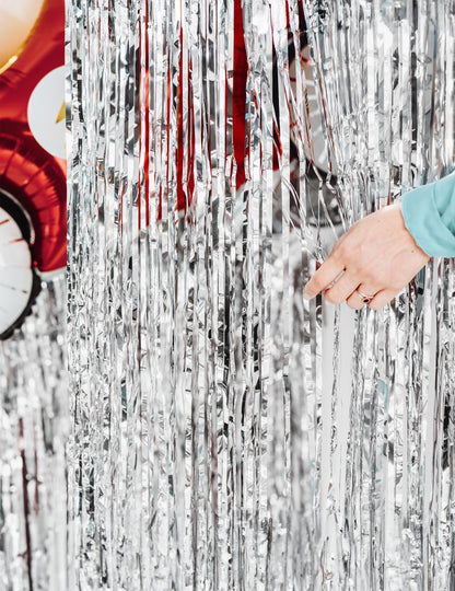 Kéz, amely az ezüst fiesztához készült fénylő függöny fröcsköléseit eltávolítja